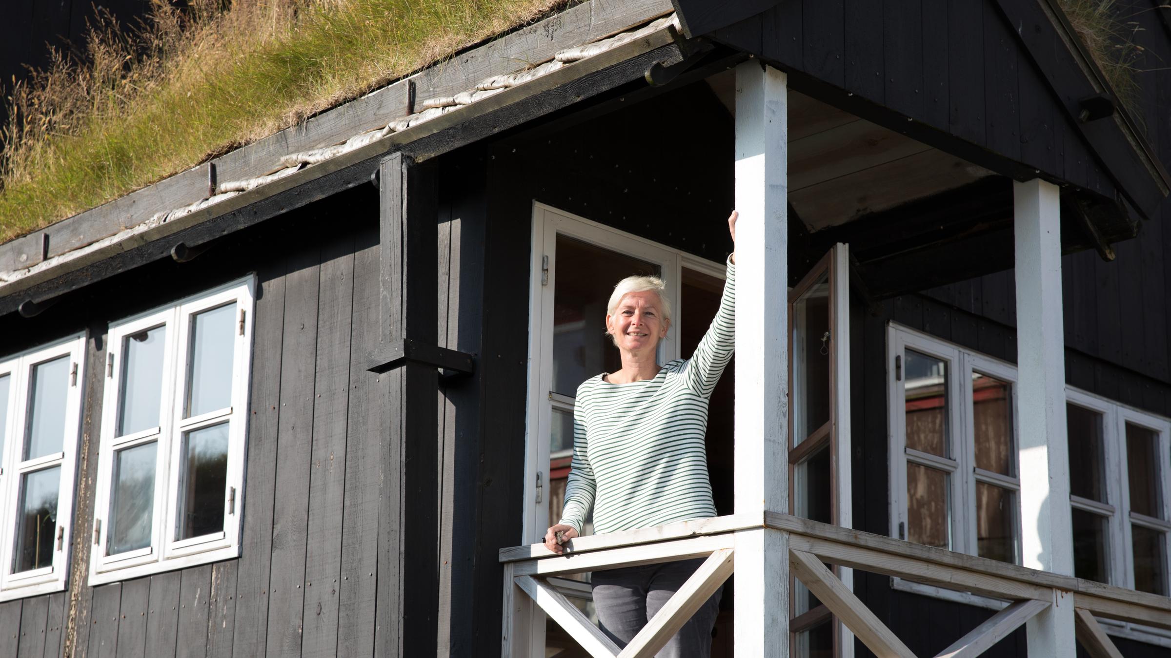 "Inseln im Regen - Sehnsucht nach den Färöern": Dörte Hansen steht auf der Veranda eines Holzhauses.