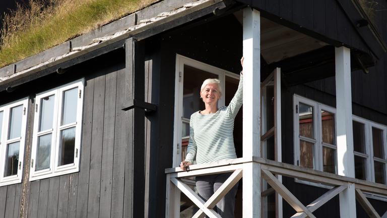 "Inseln im Regen - Sehnsucht nach den Färöern": Dörte Hansen steht auf der Veranda eines Holzhauses.
