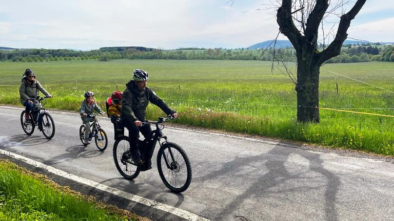 "WISO-Dokumentation: Reisen ohne Fußabdruck - wie nachhaltig kann Urlaub sein?":  Eine Familie fährt auf der Landstraße Fahrrad.