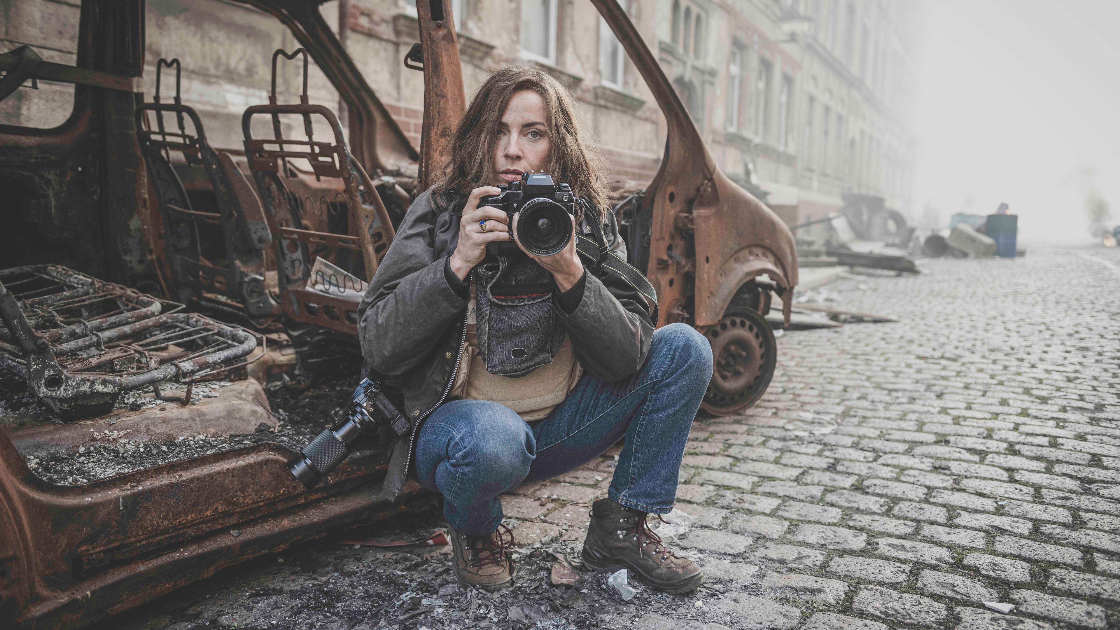 "Die Bilderkriegerin": Anja Niedringhaus (Antje Traue) sitzt vor einem ausgebranntem Auto.