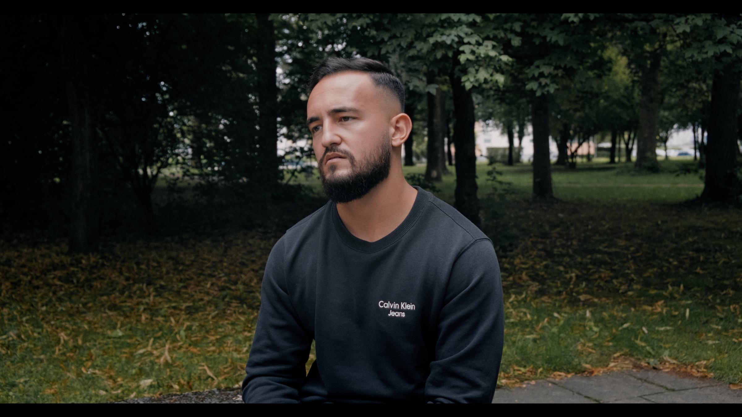 "Einzeltäter - München": Arbnor Sequashi sitzt trauernd mit hängenden Schultern in einem Park. Er blickt gedankenverloren ins Leere.