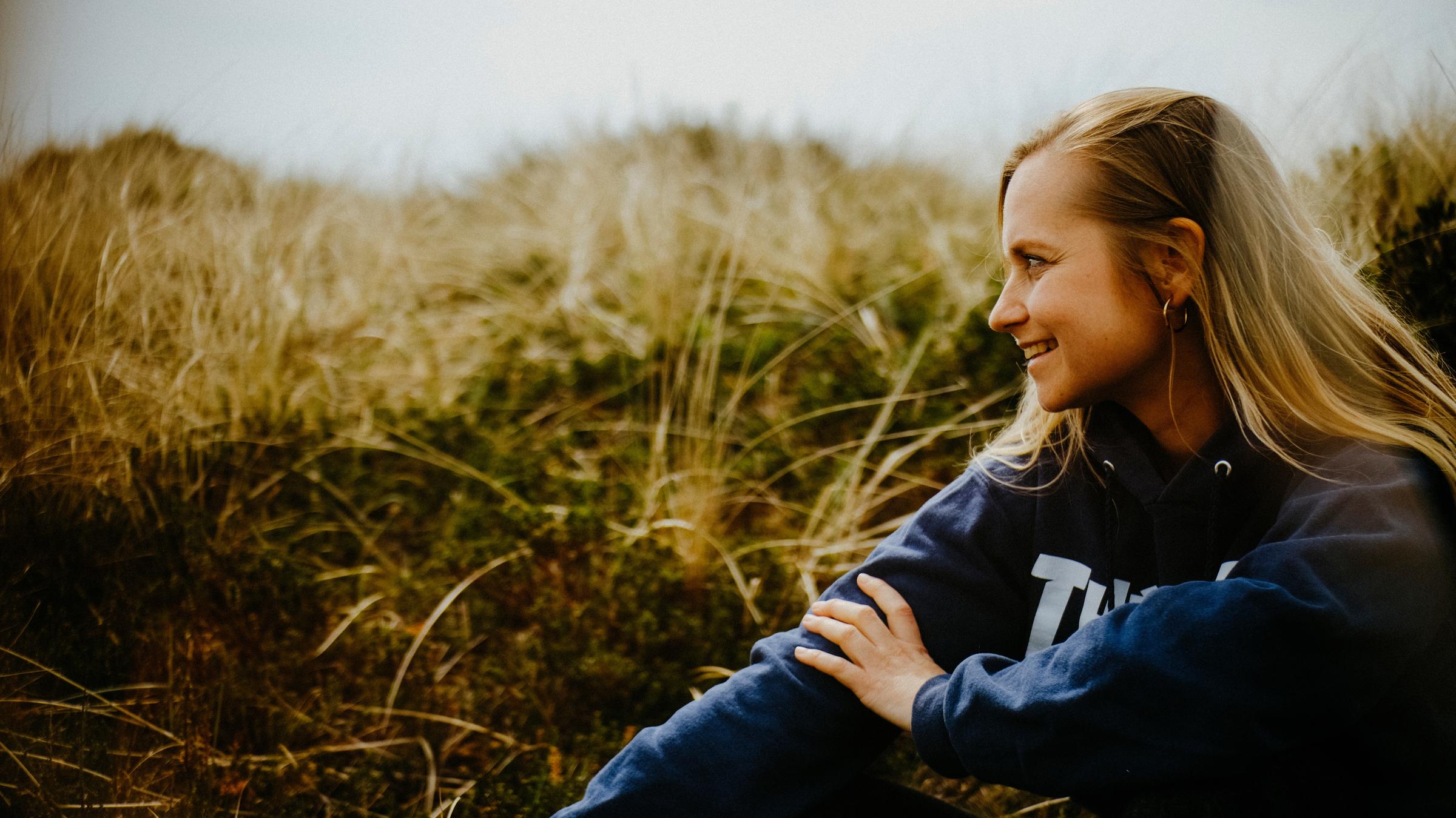 "Happy End auf Zeit - Sarah und ihr Spenderherz": Sarah Angelina sitzt in den Dünen an einem Strand.