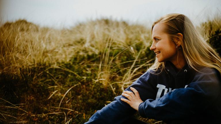 "Happy End auf Zeit - Sarah und ihr Spenderherz": Sarah Angelina sitzt in den Dünen an einem Strand.
