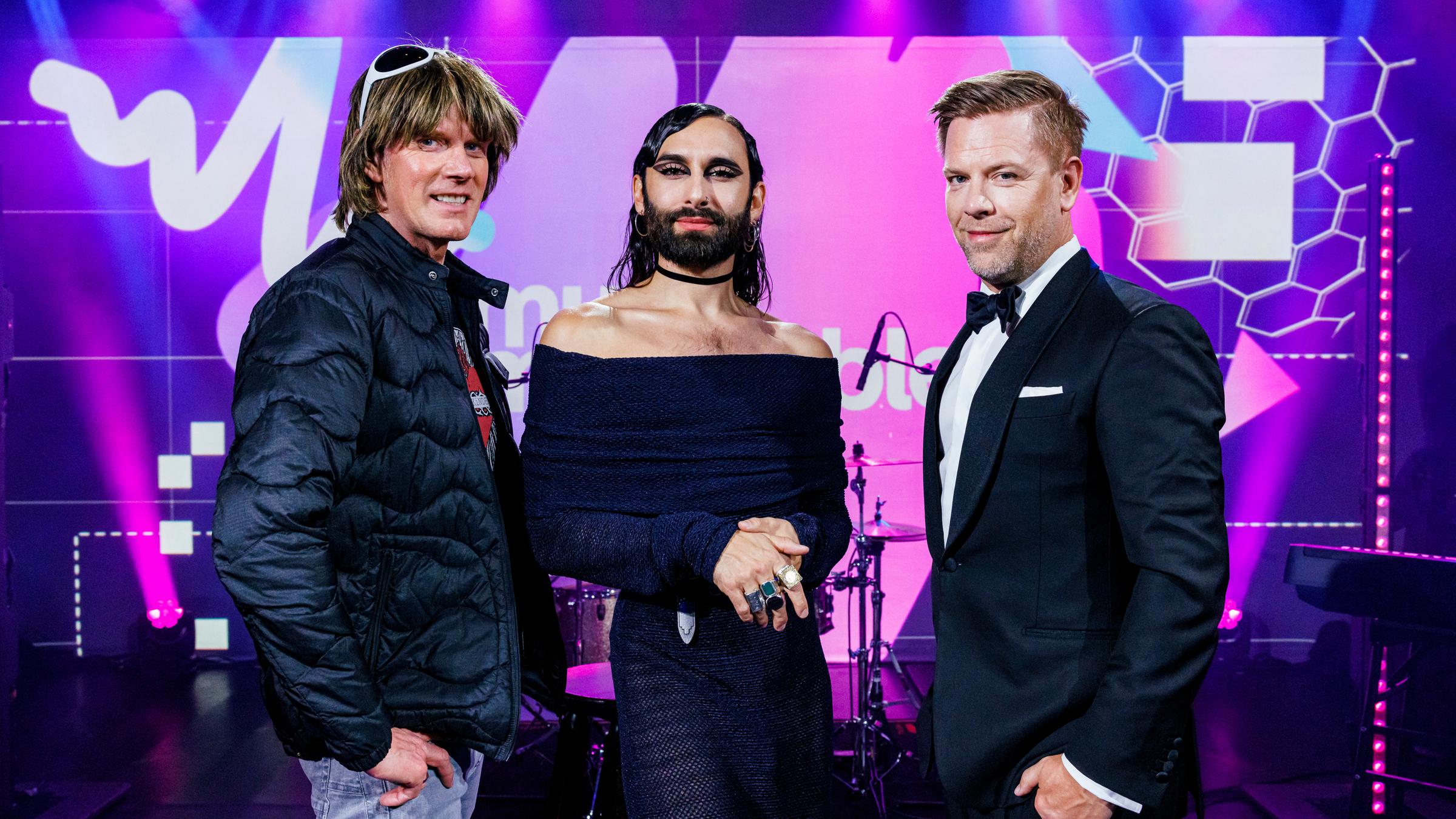 "Music Impossible - Mein Song. Dein Sound.": Mickie Krause, Conchita Wurst und Tom Gaebel stehen nebeneinander auf der Bühne und lächeln in die Kamera.