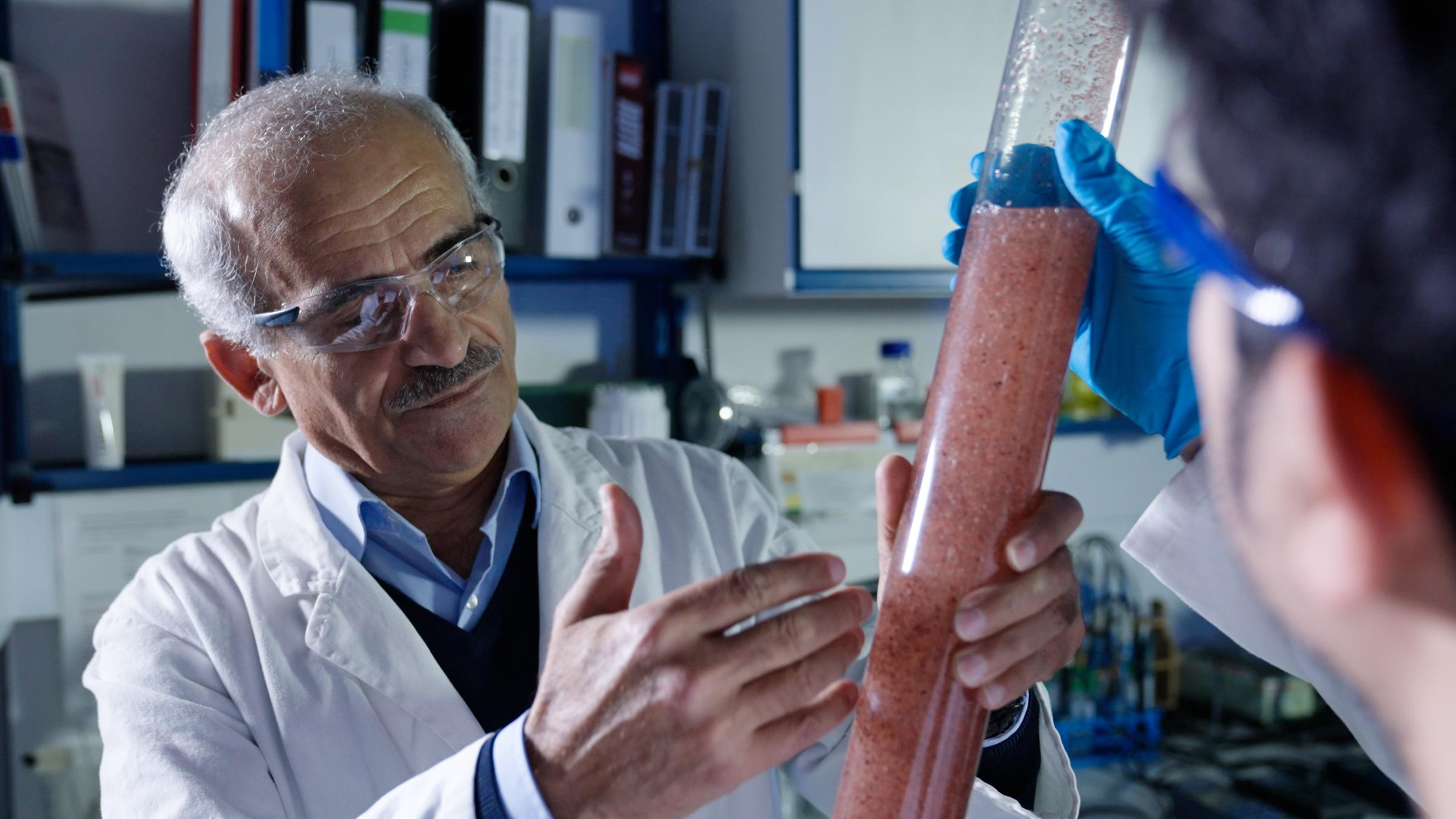 "planet e.: Fracking in Deutschland – Rettung aus der Energiekrise oder Risiko?": Prof. Amro hält im Labor einen Glaszylinder mit einer rötlichen Flüssigkeit in der Hand.