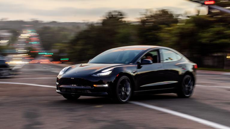"Musk auf Crashkurs - Teslas gefährliches Spiel": Ein schwarzer Tesla fährt über eine Kreuzung.