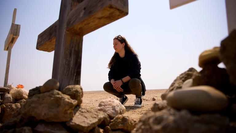 "37°: Totgerast - Wie Angehörige weiterleben": Antonia Joschkos hockt vor einem Kreuz in der Namibischen Wüste und schaut dieses an. Ein weiteres Kreuz steht mittig im Vordergrund, am rechten Bildrand ist ein weiteres Kreuz im Anschnitt zu sehen.