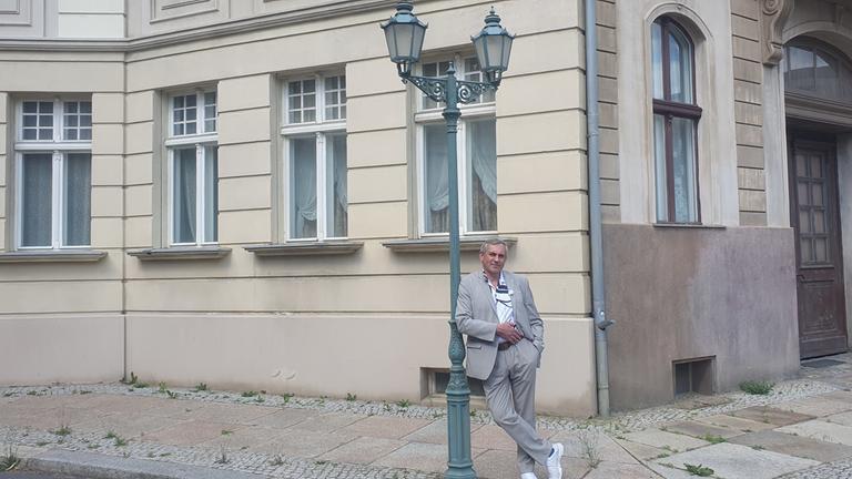 "Kaminer Inside: Filmstadt Babelsberg": Kaminer vor der Kulisse einer Berliner Straßenecke, er lehnt an einer alten Gaslaterne.