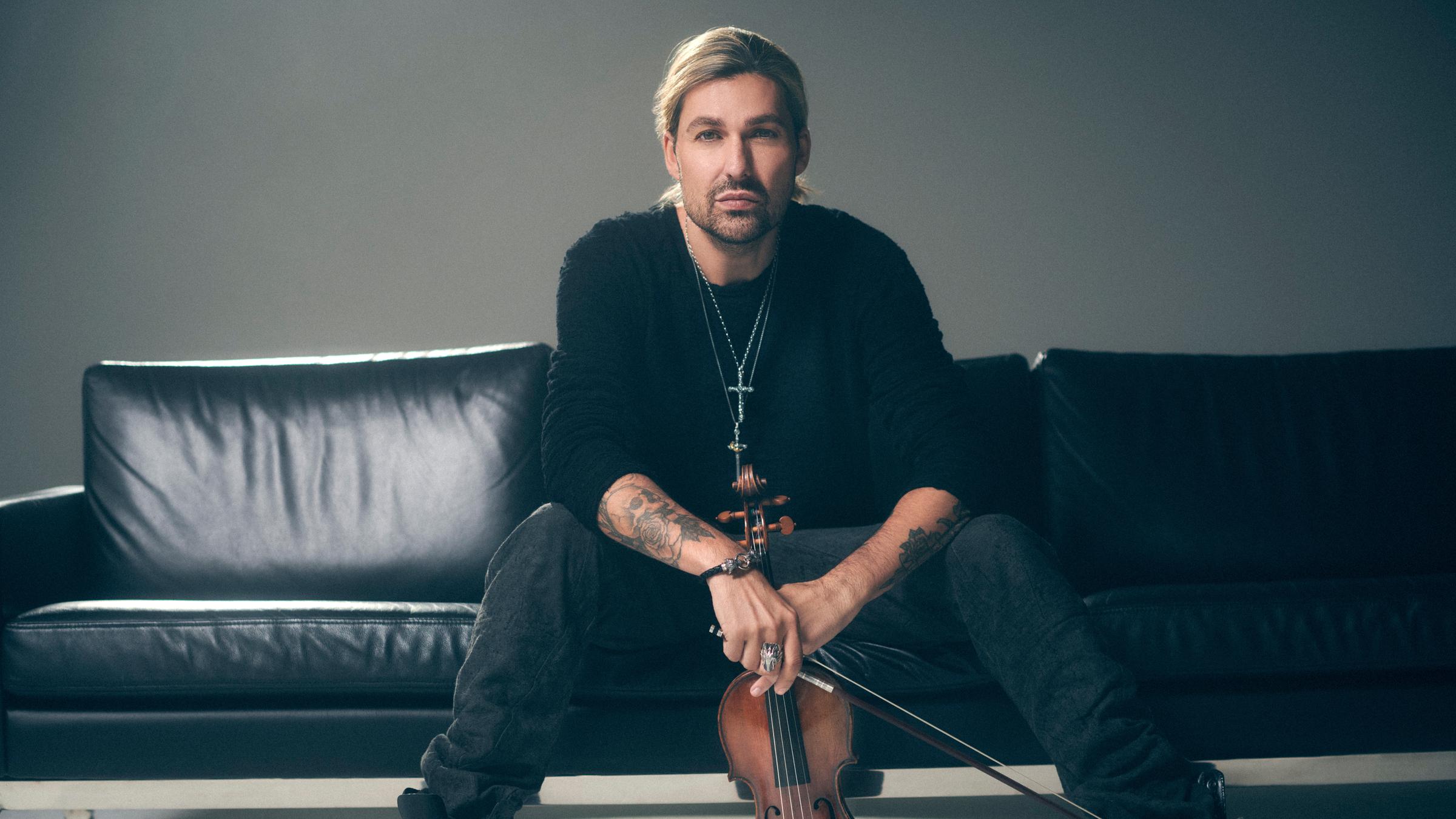 "OPUS Klassik 2023": David Garrett sitzt entspannt mit seiner Geige in der Hand auf einem schwarzen Ledersofa.