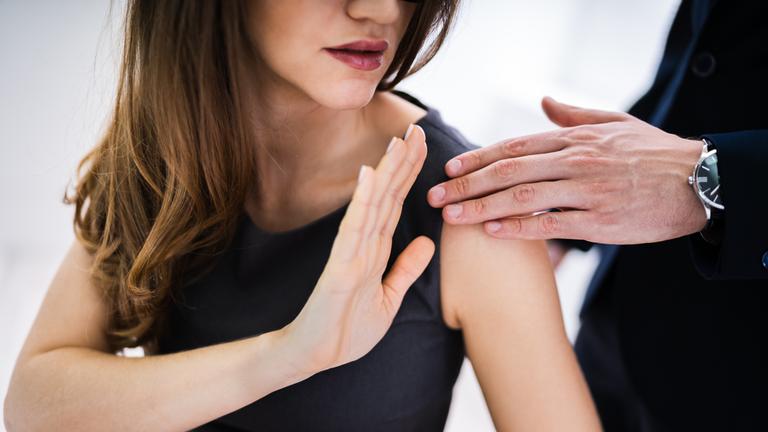 "Sex und Macht": Eine Frau im schwarzen Kleid hält ihre erhobene Hand zur Abwehr gegen die Hand eines Mannes. Beide Gesichter sind nicht zu erkennen.