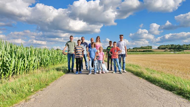 "ZDF.reportage: Familie XXL - Kinder, Chaos, Abenteuer": Gruppenfoto der Familie Dederichs auf einem Weg zwischen Feldern.