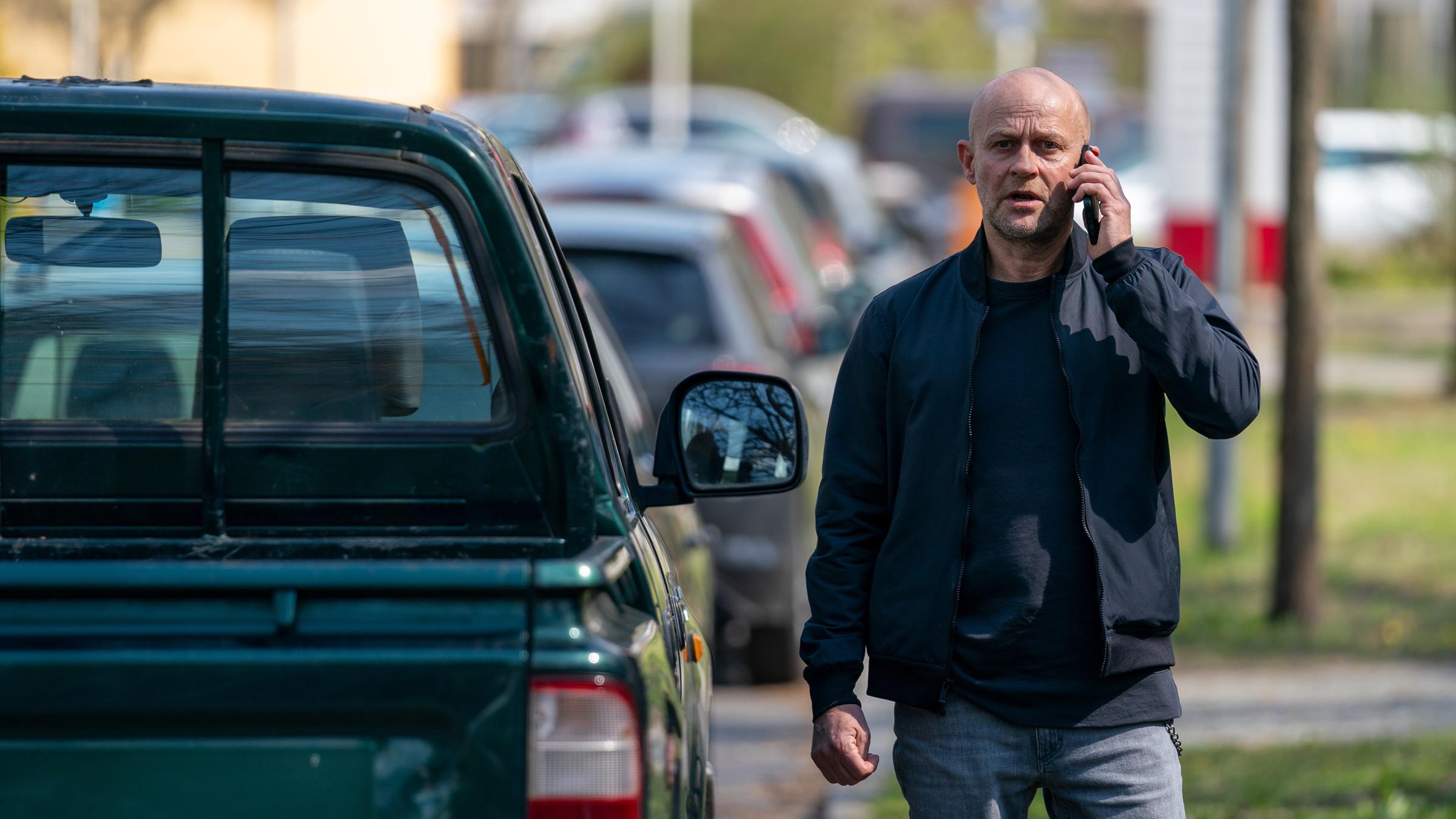 "Jenseits der Spree - Du bist mein": Robert (Jürgen Vogel) steht neben einem parkenden Auto und telefoniert mit seinem Mobiltelefon.