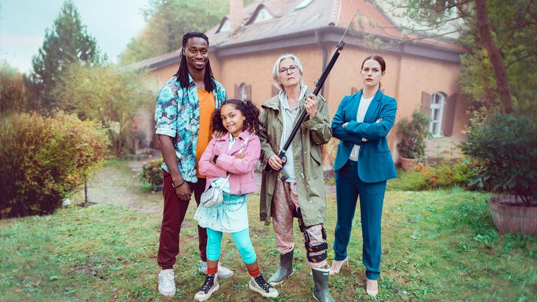  "Mit Harpunen schießt man nicht": Simon (Eugene Boateng), Feli (Muine Keune), Gerda (Gerburg Jahnke) und Linda (Isabell Polak) stehen nebeneinander vor einem Haus im Garten und schauen direkt in die Kamera.