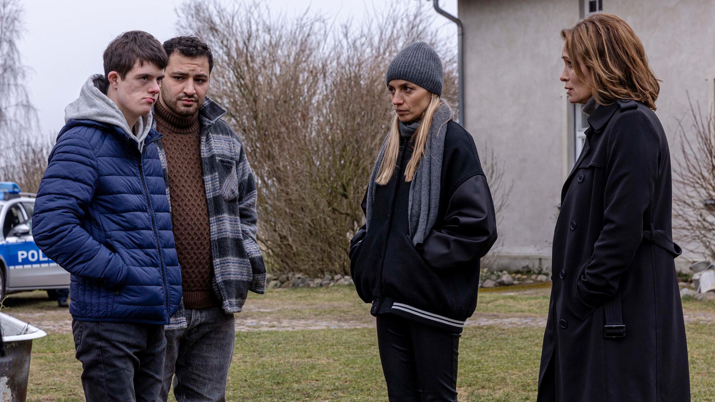  "Das Quartett - Mörderischer Pakt": Tristan Loos (Henrik Brouwers), Lutz (Walid Al-Atiyat), Pia (Annika Blendl) und Maike (Anja Kling) stehen in einem Vorgarten. Alle Blicke sind auf Tristan gerichtet, der mit zugekniffenem Mund zur Seite wegschaut.