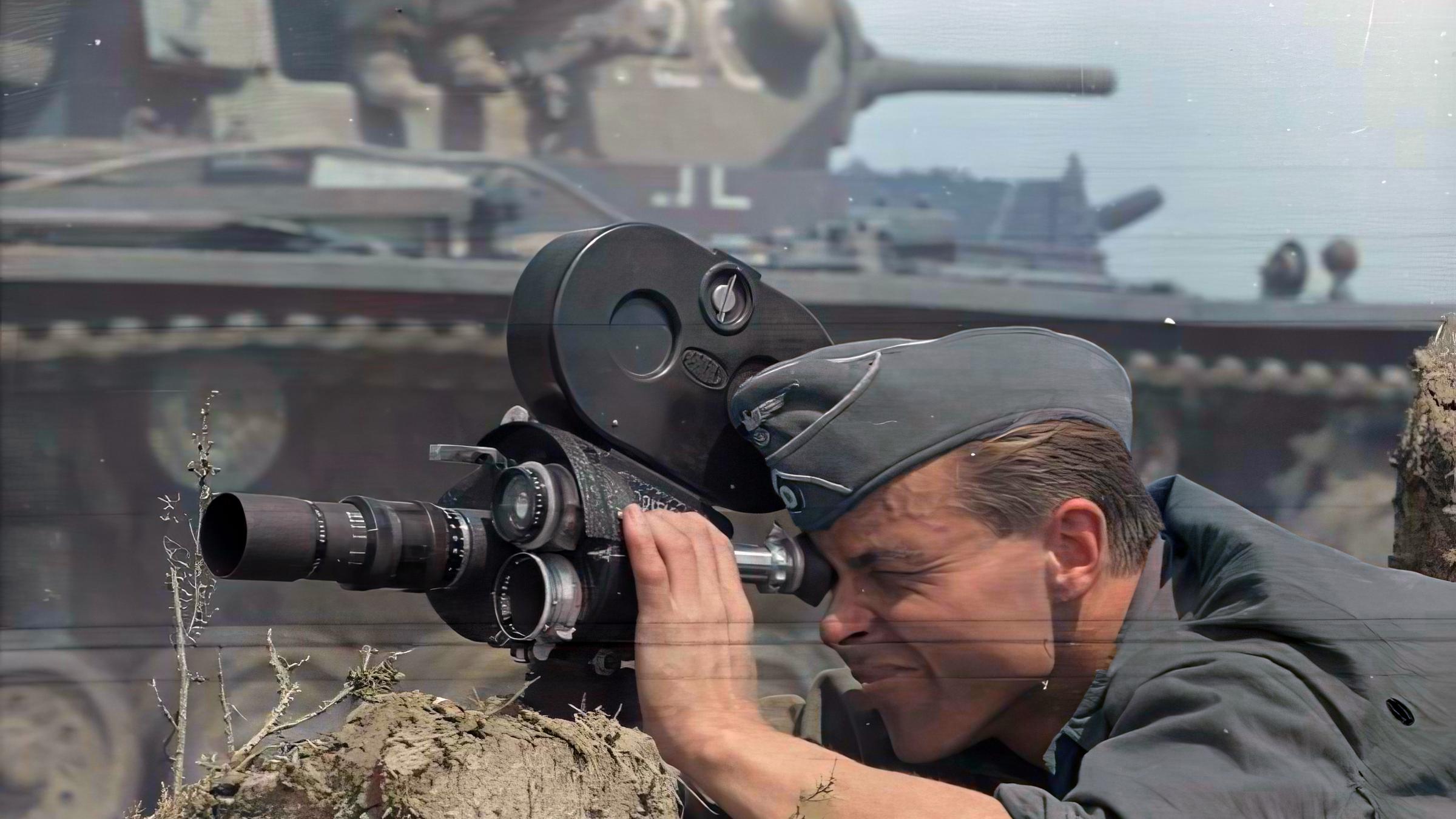 "Terra X History: Reporter in Hitlers Krieg. Von der Diktatur in die Demokratie": Coloriertes historisches Foto: Ein Soldat mit Filmkamera liegt vor einem Panzer.
