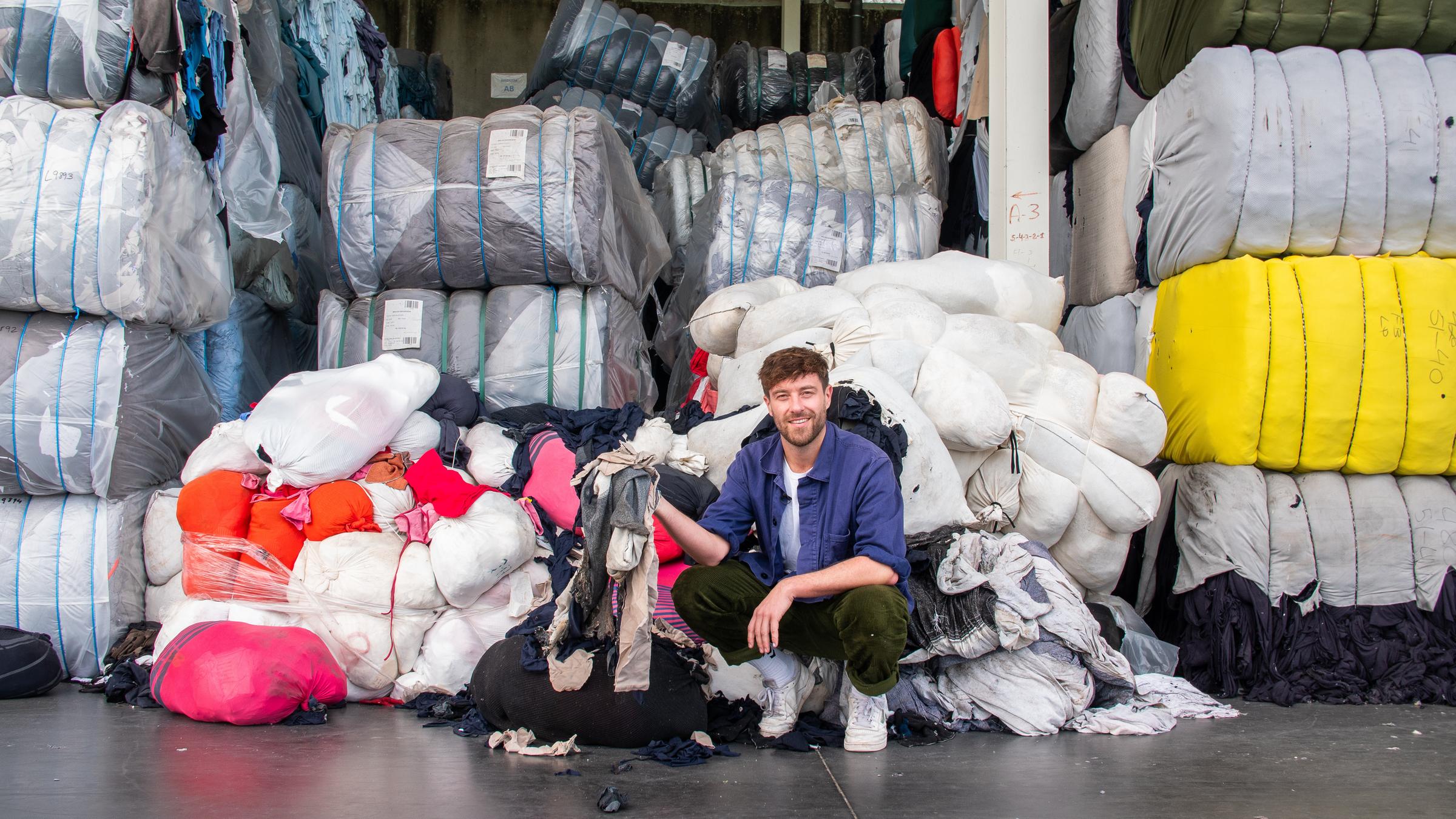 "plan b: Da geht was, Europa! - Wer bringt unsere Gesellschaft voran?": Frederik Fleig kniet vor einem Berg von Altkleidern bei Valerius in Porto.