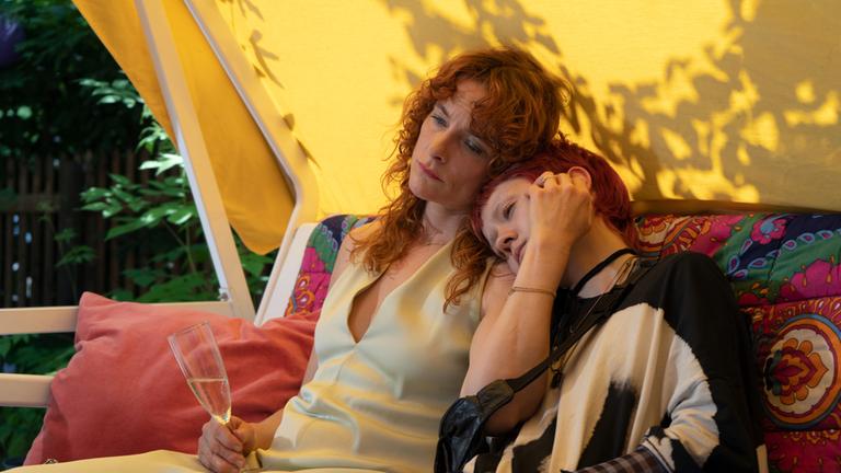 "Alle wollen geliebt werden": Mutter Ina (Anne Ratte-Polle) führt auf der  Hollywoodschaukel ein Gespräch mit ihrer Teenagertochter Elli (Lea Dindra), die den Kopf an die Schulter ihrer Mutter lehnt.