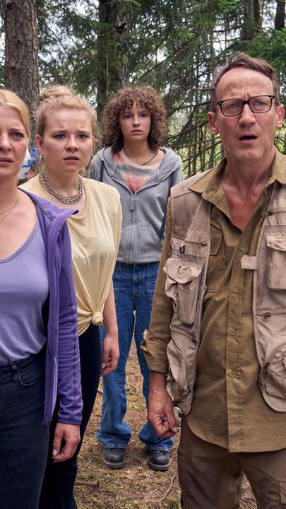 "Blackout bei Wellmanns": Thomas Wellmann (Wotan Wilke Möhring), Eva (Jördis Triebel), Paula (Daria Vivien Wolf) und Jenny (Josefine Keller) stehen auf einer Waldlichtung. Thomas trägt Funktionskleidung, die restlichen Familienmitglieder einfache Klamotten. Die Familie blickt mit erstaunten Gesichtern nach vorne.