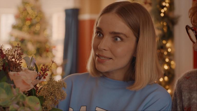 "Single Bells - 12 Dates till Christmas: Secret Santa": Mina (Julie Van den Steen) in Nahaufnahme. Sie schaut überrascht nach links aus dem Bild.