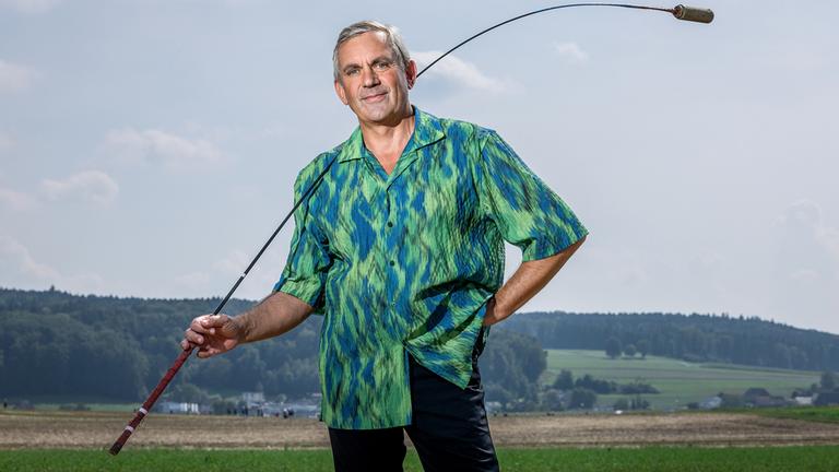 "Kaminer Inside: Brauchtum in der Schweiz": Wladimir Kaminer beim Hornussen. Das Spiel besteht für die schlagende Mannschaft darin, eine Kunststoffscheibe (den «Hornuss» oder kurz «Nouss») so weit wie möglich zu schlagen.