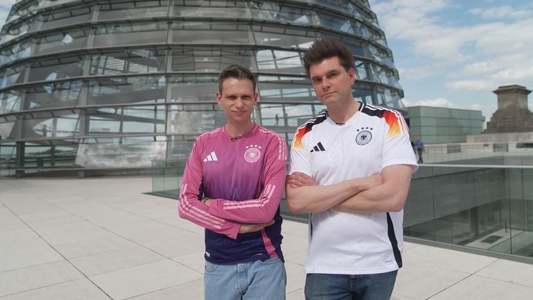 "heute-show spezial - Fußball - Ein Ball für zwei": Fabian Köster und Lutz van der Horst stehen im Dress der Fußball-Nationalmannschaft vor der Reichstagskuppel in Berlin.