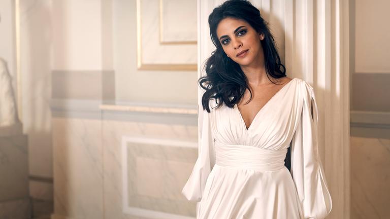 "Festkonzert aus der Semperoper Dresden 2024": Fatma Said steht im weißen Abendkleid an einer weißen Säule in einem mit Marmor getäfelten Raum. Sie blickt lächelnd in die Kamera, der Kopf ist leicht geneigt.