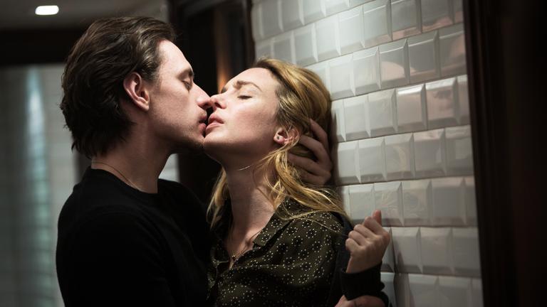 „Passion Simple“: Hélène (Lætitia Dosch) befindet sich mit dem Rücken zu einer Wand, die von oben beleuchtet ist. Alexandre (Sergej Polunin) steht ihr gegenüber und hält sie am linken Handgelenk fest, kurz bevor er sie küsst.