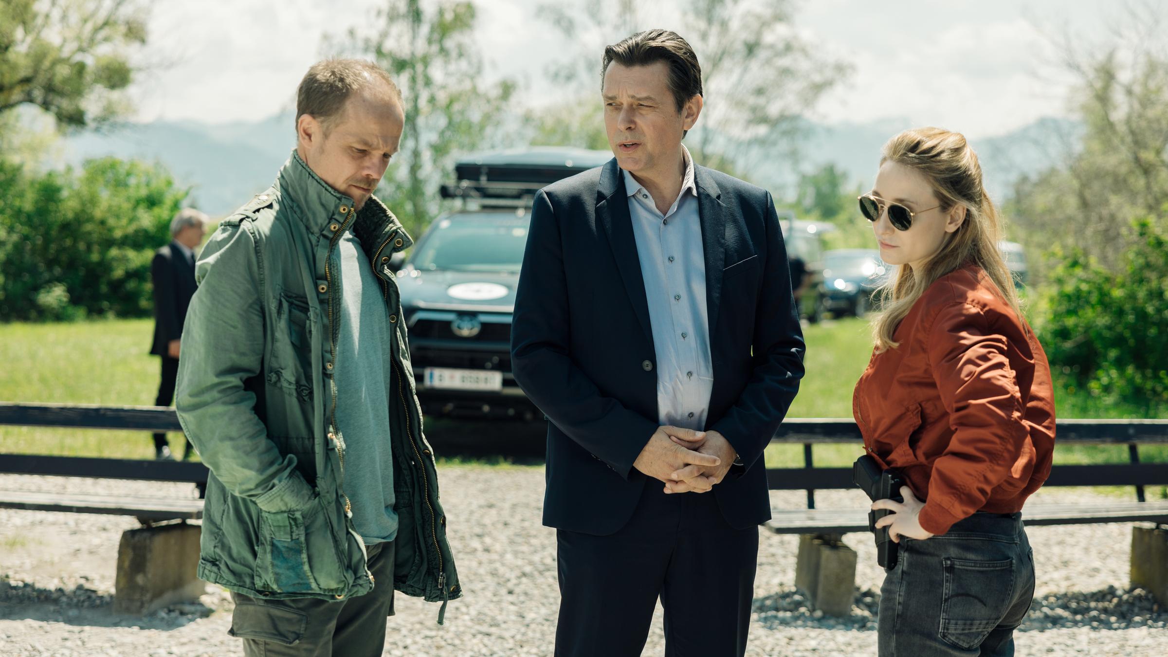 "Die Toten vom Bodensee - Atemlos": Micha Oberländer (Matthias Koeberlin), Thomas Komlatschek (Hary Prinz) und Luisa Hoffmann (Alina Fritsch) stehen draußen auf einem Parkplatz zusammen und unterhalten sich.