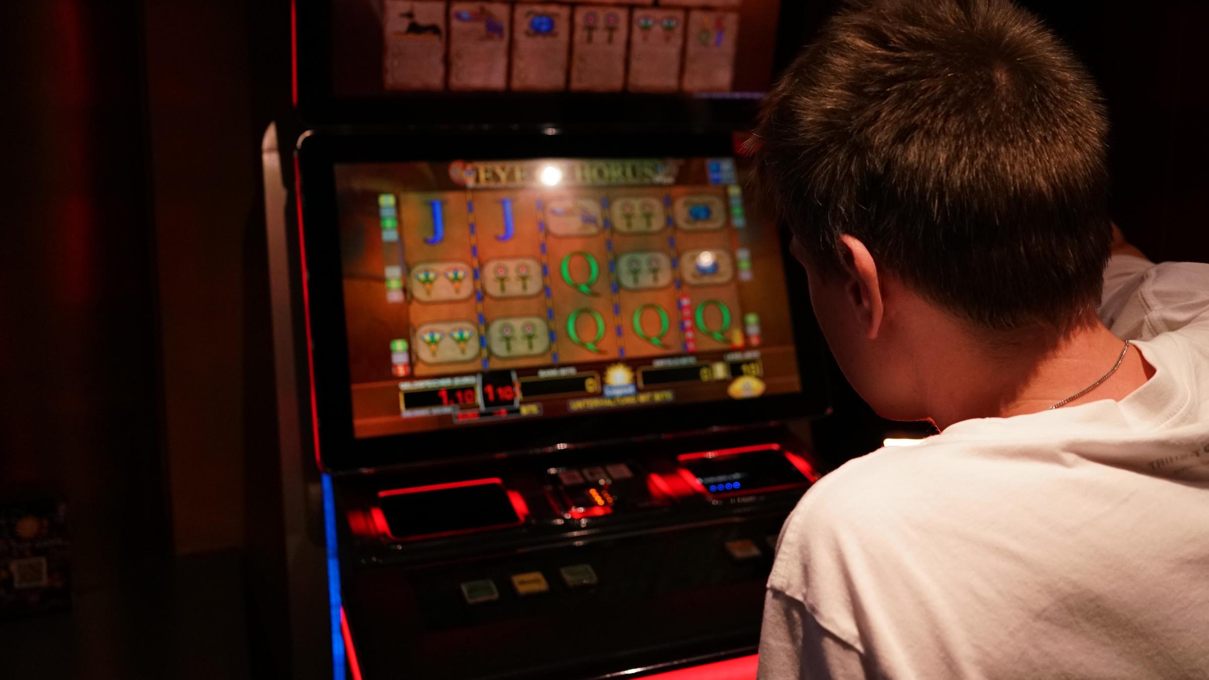 ZDF.reportage: Vorsicht Glücksspiel! - Zocken bis zur Pleite": Ein Mann mit weißem Shirt sitzt vor einem Glücksspiel-Automaten.