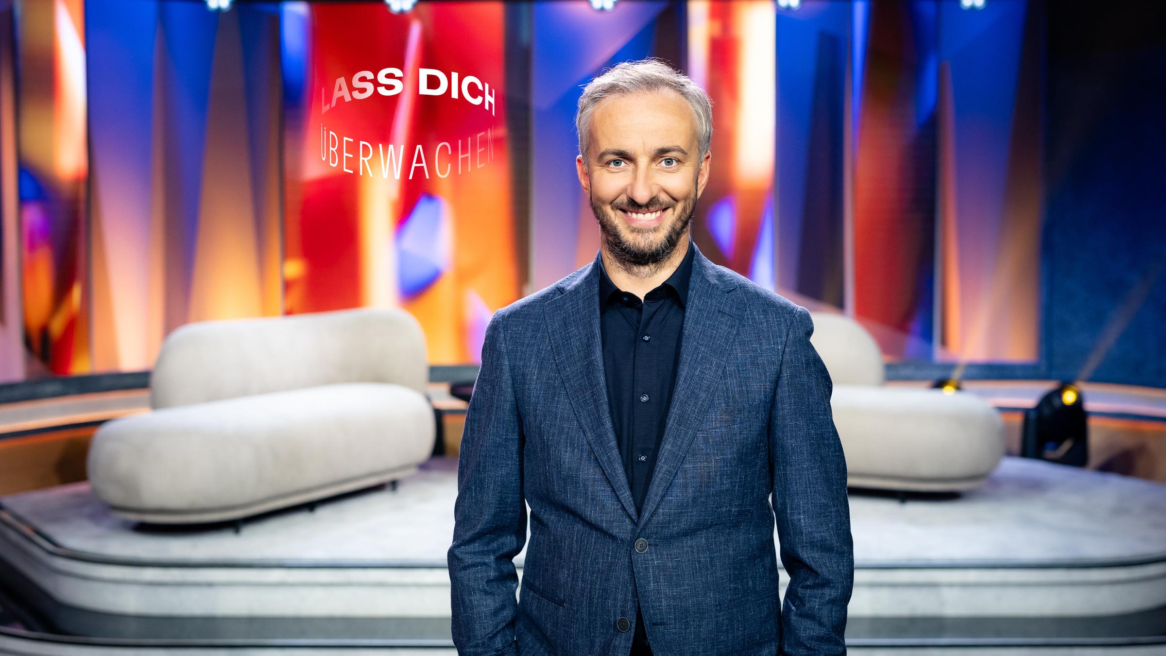 "Lass dich überwachen!": Jan Böhmermann steht im Studio und lacht in die Kamera.
