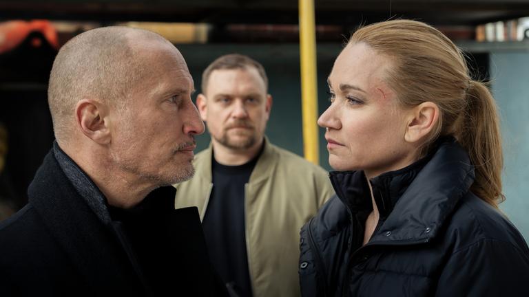  "Sarah Kohr - Zement": Lothar Lessen (Benno Fürmann) und Sarah Kohr (Lisa Maria Potthoff) stehen sich gegenüber und schauen sich feindselig an. Zwischen den beiden im Hintergrund steht Achim Wieczorek (Florian Schmidtke), der Sarah ansieht.