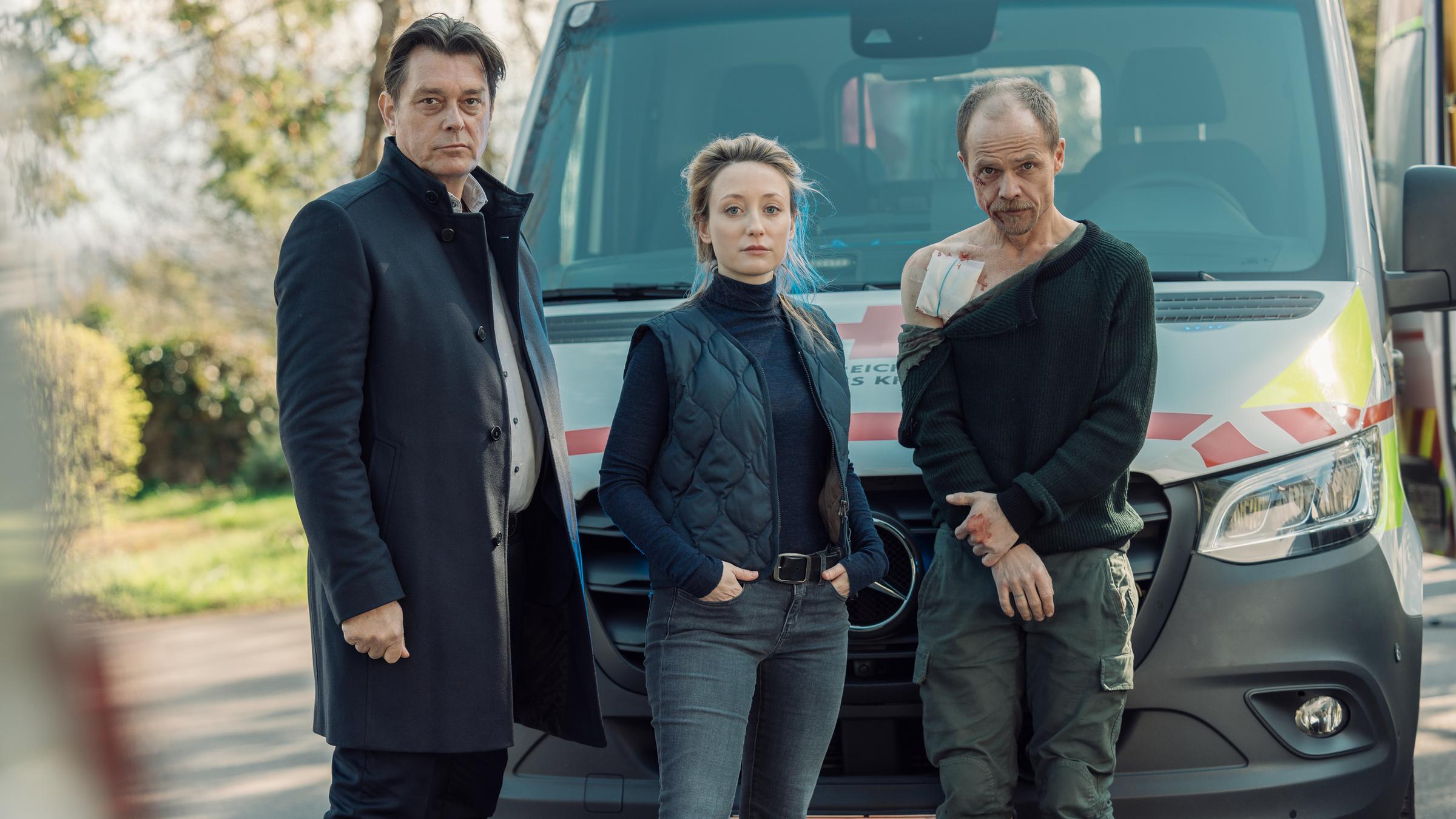 "Die Toten vom Bodensee - Die Messias": Micha Oberländer (Matthias Koeberlin), Luisa Hoffmann (Alina Fritsch) und Thomas Komlatschek (Hary Prinz) stehen zusammen vor einem Notarztwagen. Micha Oberländer (Matthias Koeberlin) ist verletzt.