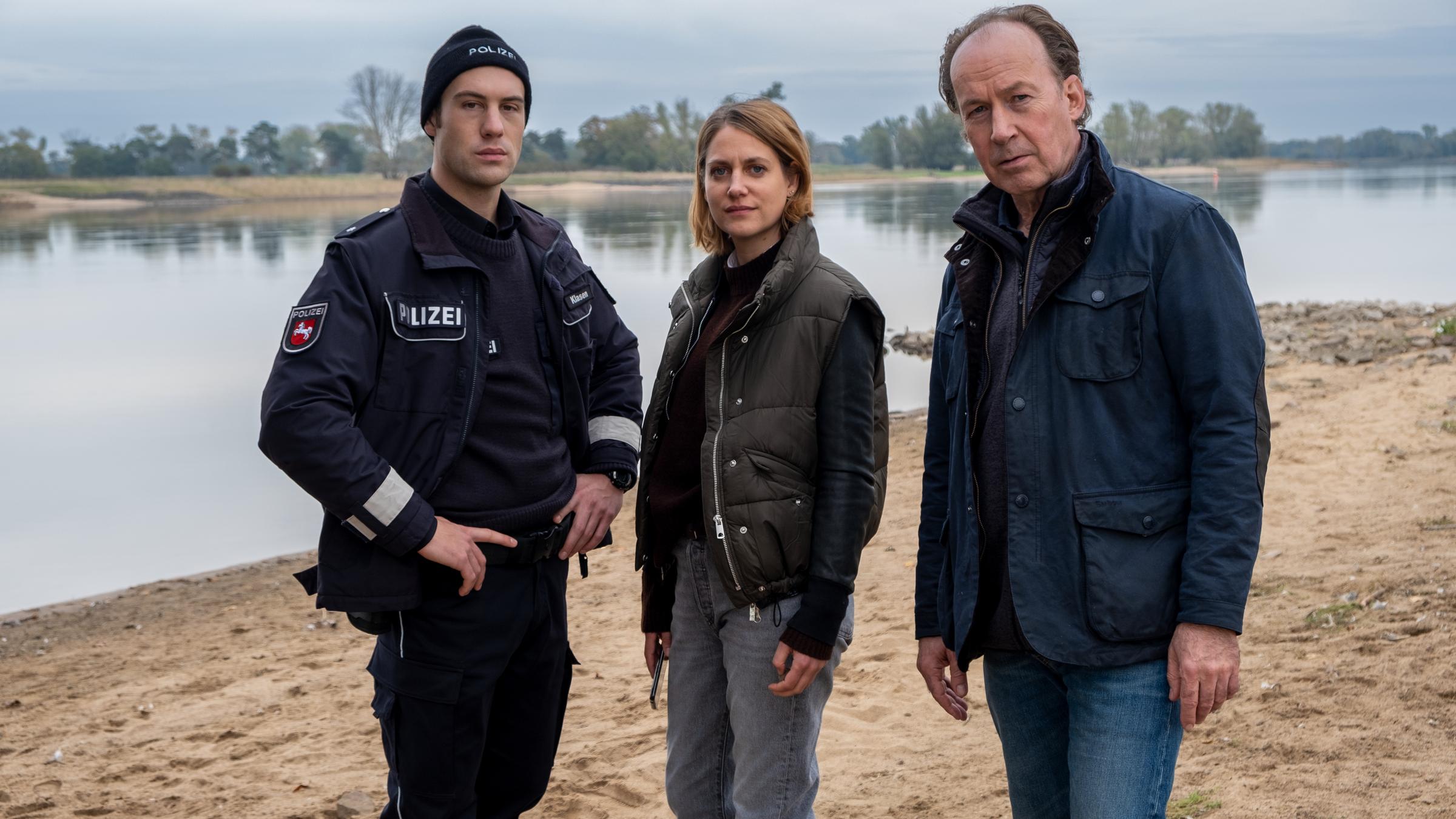"Wendland - Stiller und das große Schweigen": Oliver Klasen (Malte Thomsen), Kira Engelmann (Bettina Burchard) und Jakob Stiller (Ulrich Noethen) stehen zusammen am Ufer.