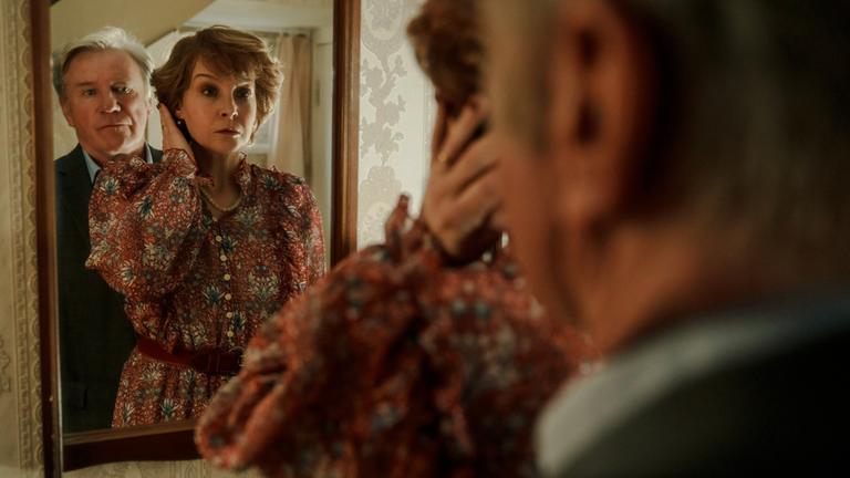 "Der Fall Marianne Voss": Marianne (Valerie Koch) steht am Spiegel und fährt sich mit der linken Hand durchs Haar. Links hinter ihr steht Karsten (Jörg Schüttauf) und blickt über ihre Schulter in den Spiegel.