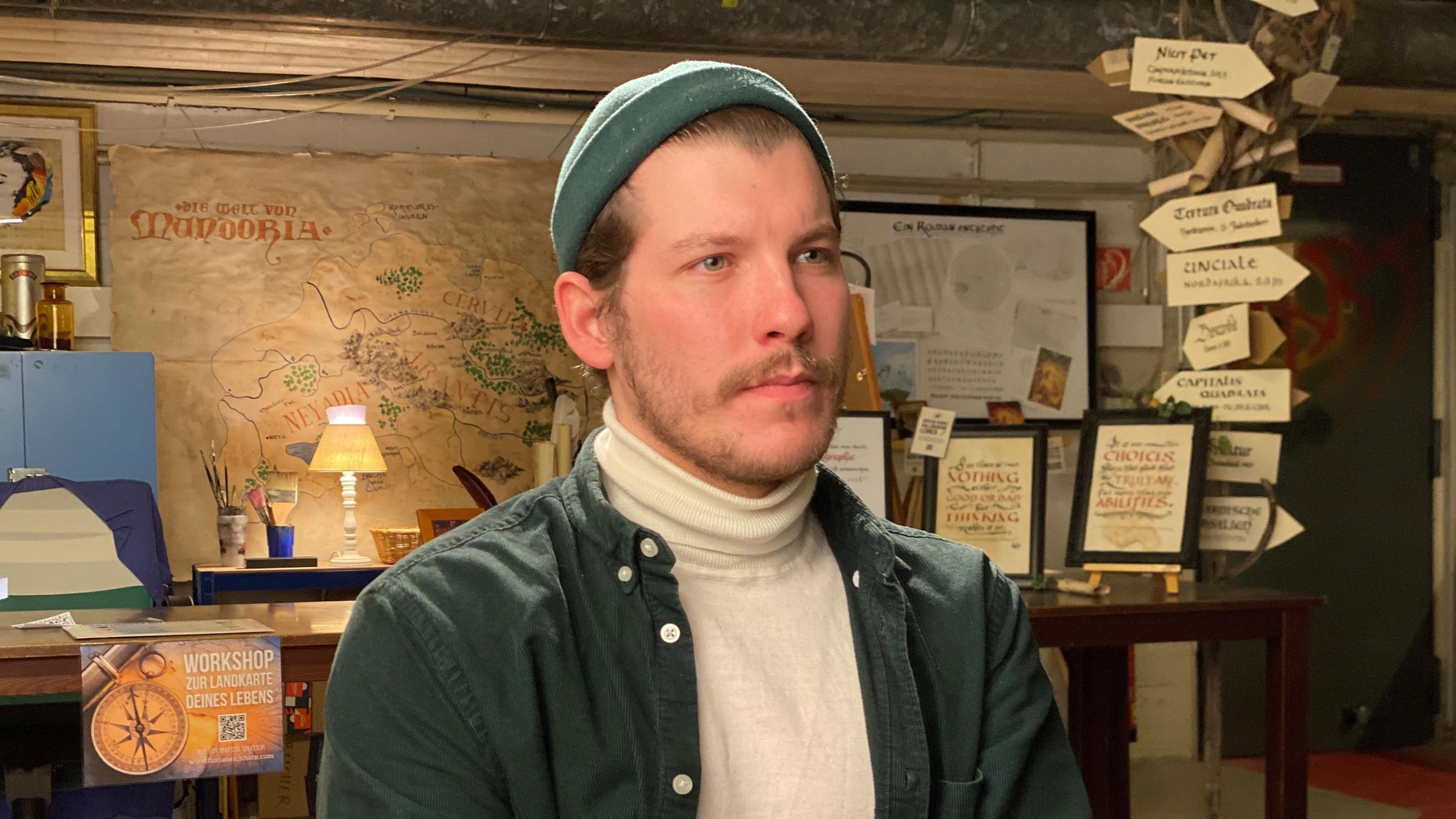 "Schock Schalom – jung, jüdisch, jetzt": Anton, mit Dreitagebart und Wollmütze, sitzt in einem Kunstatelier auf einem Stuhl und blickt zur Seite.