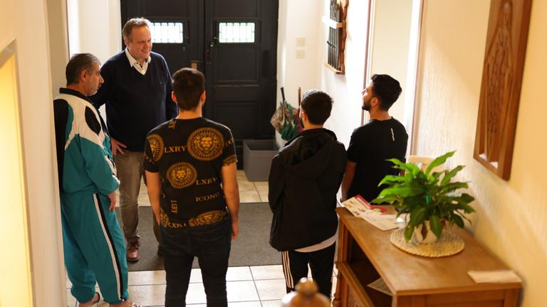 "Letzte Hoffnung Kirchenasyl": Eine Gruppe von Männern bespricht sich im Hausflur.