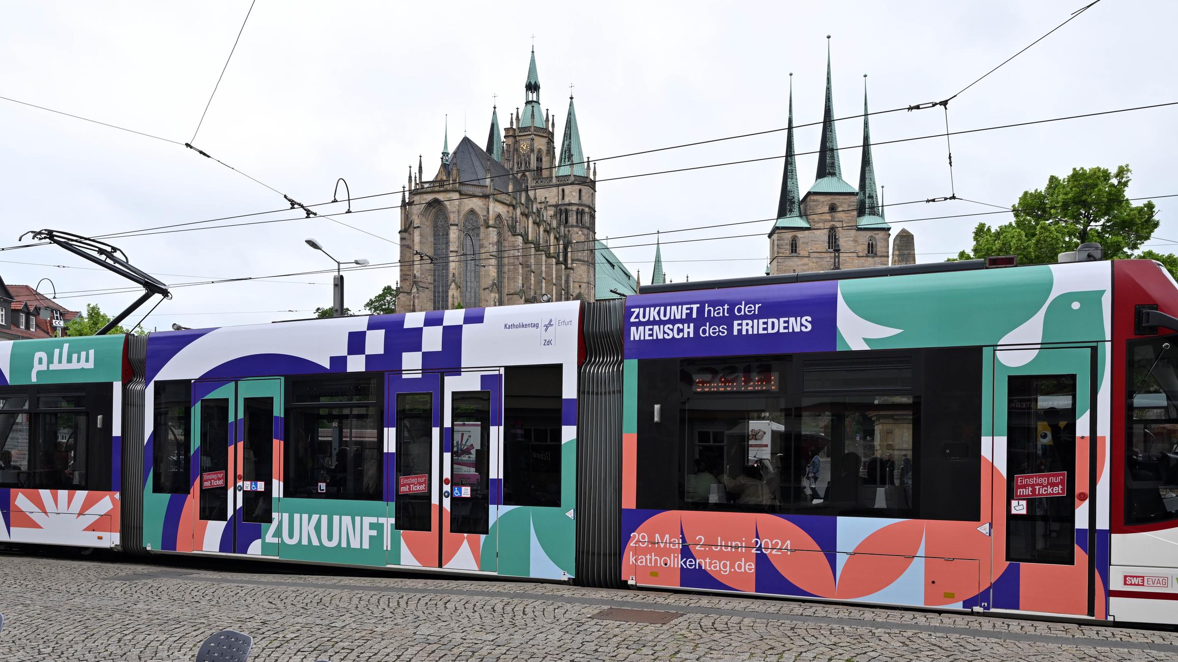  "Katholisch für fünf Tage – Der Katholikentag 2024 in Erfurt": Das Leitwort des Katholikentags "Zukunft hat der Mensch des Friedens" ist auf einer bunt beklebten Straßenbahn angebracht, als Teil einer Werbekampagne des 103. Deutschen Katholikentags in Erfurt.