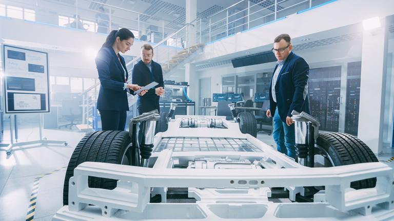 "WISO: Autoland in der Krise - Wie Deutschland den Neustart versucht": Drei Personen stehen um einen Autokonstruktion mit Batteriezellen in einer Werkshalle.