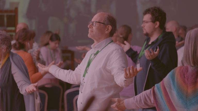 "Die Welt der Coaches: Mach mich glücklich!": Ein Mann, der sich auf einem spirituellen Festival befindet und mit ausgebreiteten Armen stehend meditiert.
