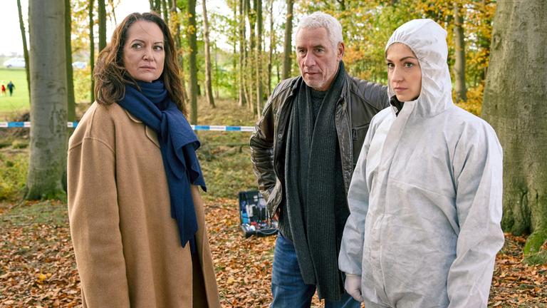 "Unter anderen Umständen - Nordwind": Jana Winter (Natalia Wörner), Matthias Hamm (Ralph Herforth) und Rechtsmedizinerin (Sophia Schubert) stehen an einem Tatort im Wald.