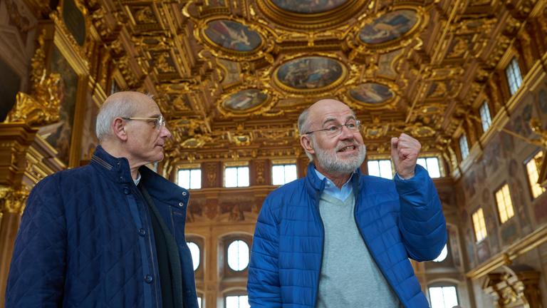 "Lesch sieht Schwartz: FOMO - die Angst etwas zu verpassen": Thomas Schwartz und Harald Lesch stehen in einem Prunksaal.