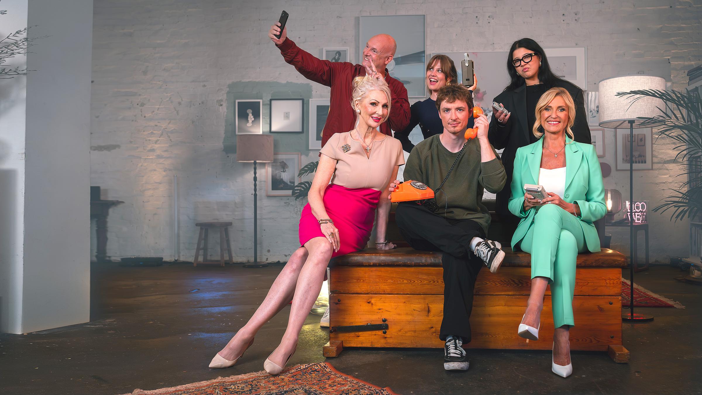 "Wir waren fleißig! Ihr seid faul? - Der große Generationen-Streit": Eine Gruppe von Personen unterschiedlichen Alters sitzt auf einem Hocker oder steht dahinter. Alle halten verschiedene Gegenstände aus verschiedenen Epochen in den Händen. Von links: Kabarettistin Désirée Nick (67), Moderator Frank Buschmann (59), Influencerin Isabelle Vivianne (26), Musiker Roman Lochmann (25), Podcasterin und Journalistin Yasmine M'Barek (25) sowie Unternehmerin Dagmar Wöhrl (70)