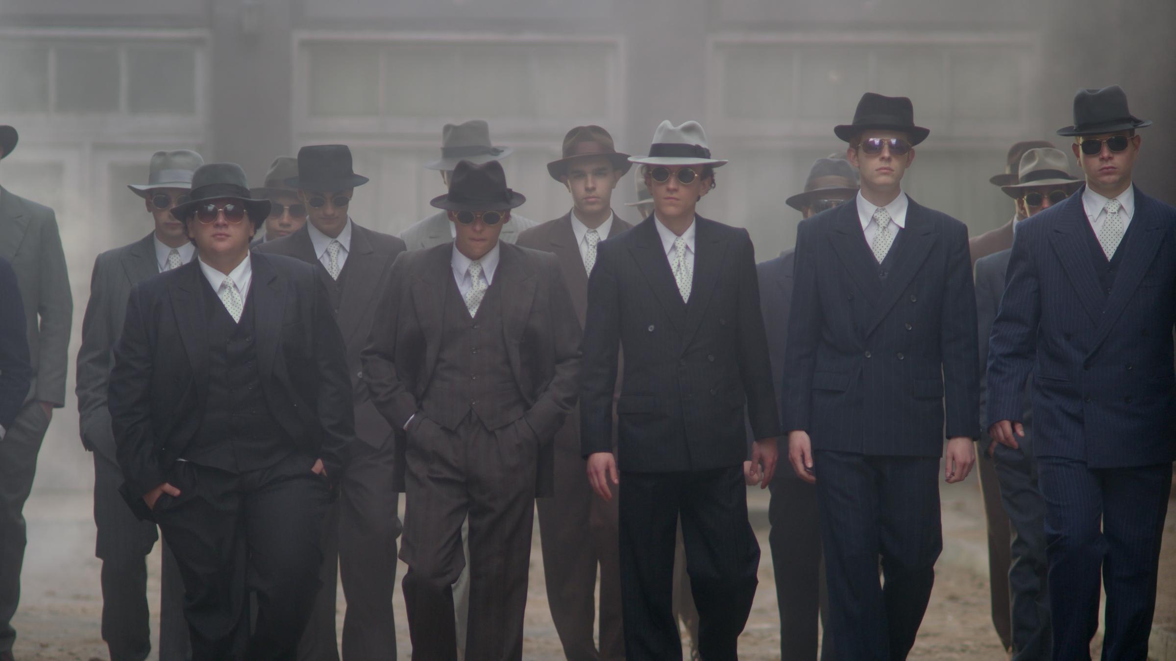 „XY history: Kaum zu fassen – die Gladow-Bande“: Aufnahme einer Reenactment-Szene, in der die Bande in Anzug, mit gepunkteten Krawatten und Hüten zu sehen ist.