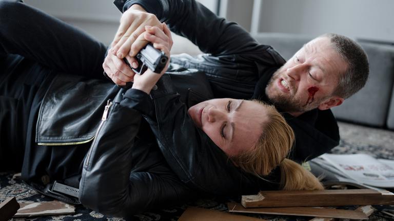 "Sarah Kohr - Koma": Sarah Kohr (Lisa Maria Potthoff) kämpft auf dem Boden liegend mit Tim Schulmann (Adrian Topol) um eine Pistole. Tim Schulmann hat eine Wunde an der Wange.