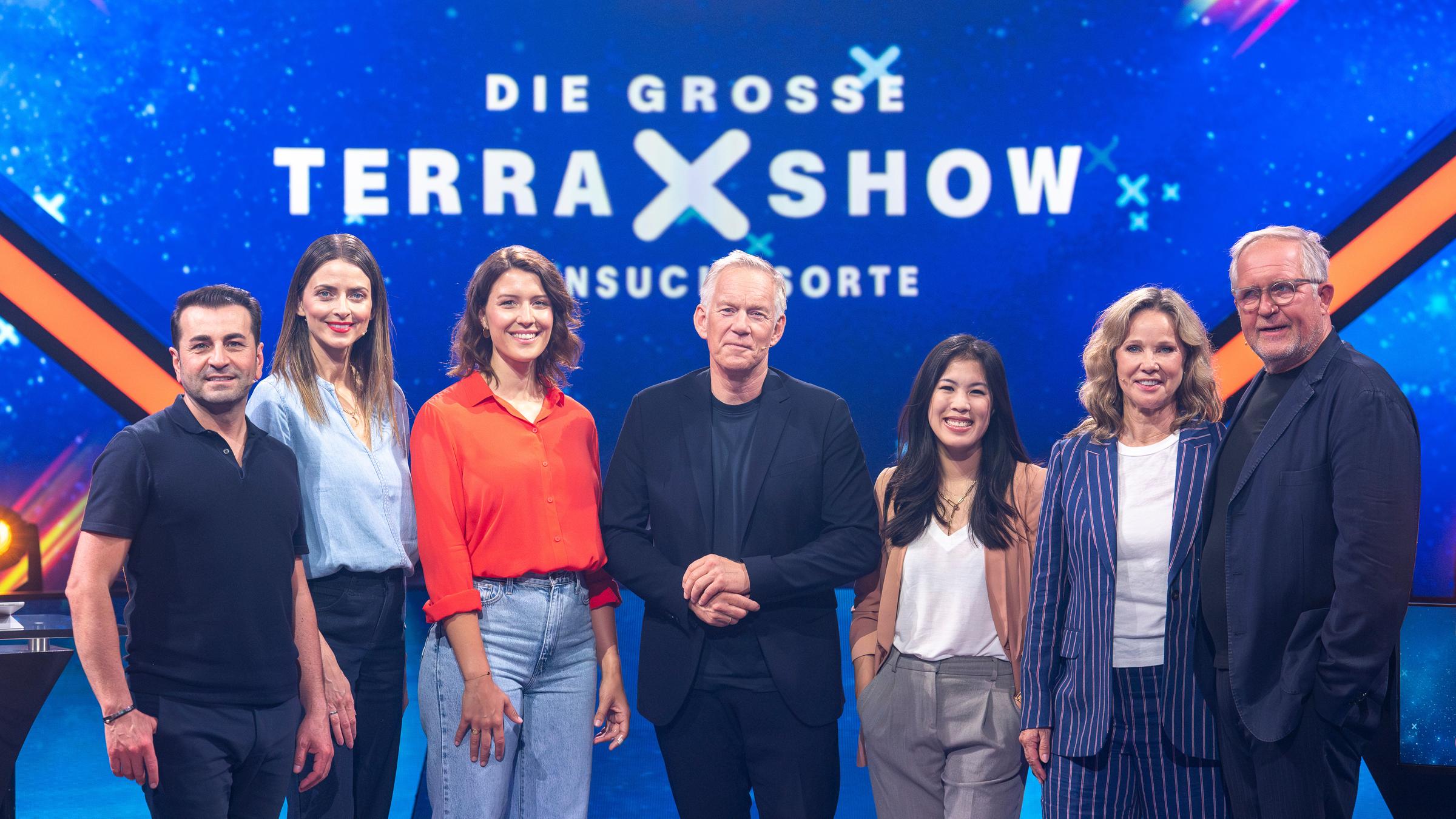"Die große "Terra X"-Show - Sehnsuchtsorte": Ali Güngörmüş, Eva Padberg, Hannah Emde, Johannes B. Kerner, Mai Thi Nguyen-Kim, Ann-Kathrin Kramer und Harald Krassnitzer stehen vor dem Sendungslogo im Studio und lächeln in die Kamera.