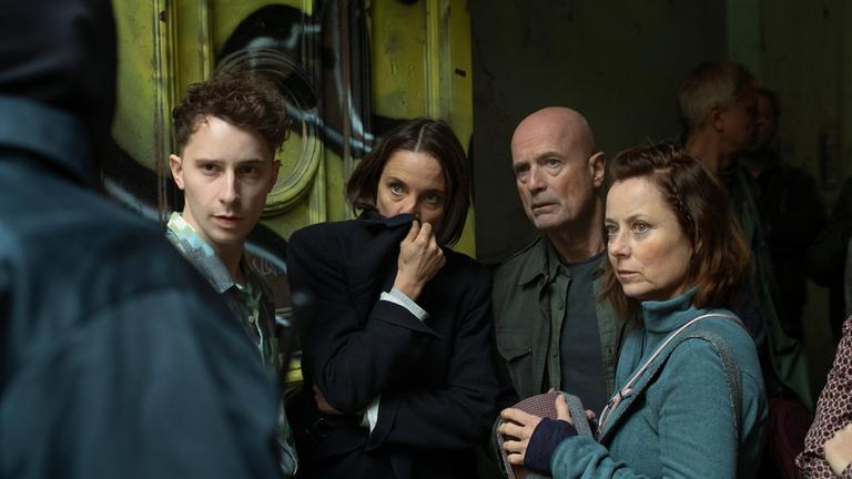 "Black Box": Elias Levy (Jonathan Berlin), Caroline Hahn (Anne Ratte-Polle), Erik Behr (Christian Berkel) und Nikol Lang (Inka Friedrich) blicken ungläubig auf den vermummten Polizisten, der von ihnen steht.