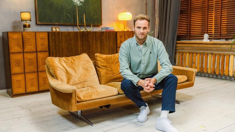 "Auf der Couch mit Dr. Leon Windscheid": Leon Winterscheid sitzt auf einem Sofa und schaut in die Kamera.