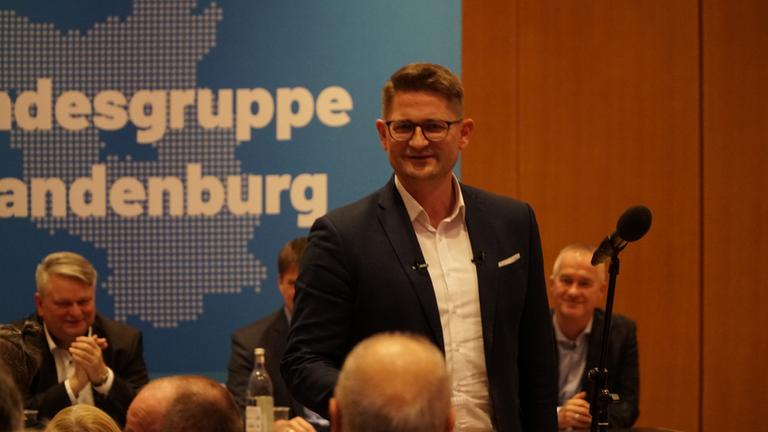 "Zwischen TikTok und Wahlurne - Der Kampf um junge Wähler": René Springer steht lächelnd in einem Raum mit anderen Personen.