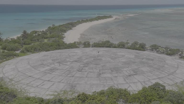 "planet e.: Kalter Krieg und Klimawandel - Atommüll in der Südsee": Luftbild: Johannes Hano steht auf der Betonkuppel des Runit-Dome. Man sieht ihn nur als kleinen Punkt auf der Betonkuppel.