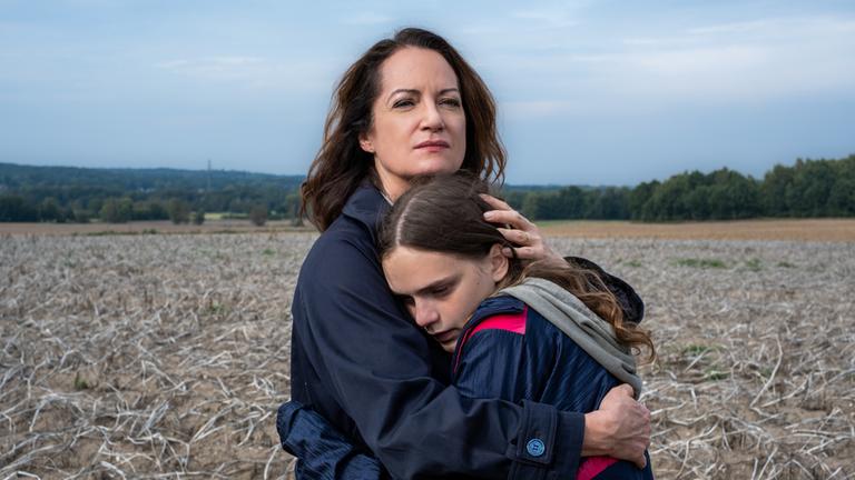 "Unter anderen Umständen – Die einzige Zeugin": Jana Winter (Natalia Wörner) stht im Feld und umarmt Lea Hansen (Mariella Aumann) .
